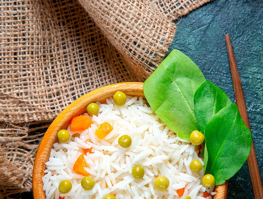 Un plato con arroz blanco hervido, guisantes y zanahoria hervida.