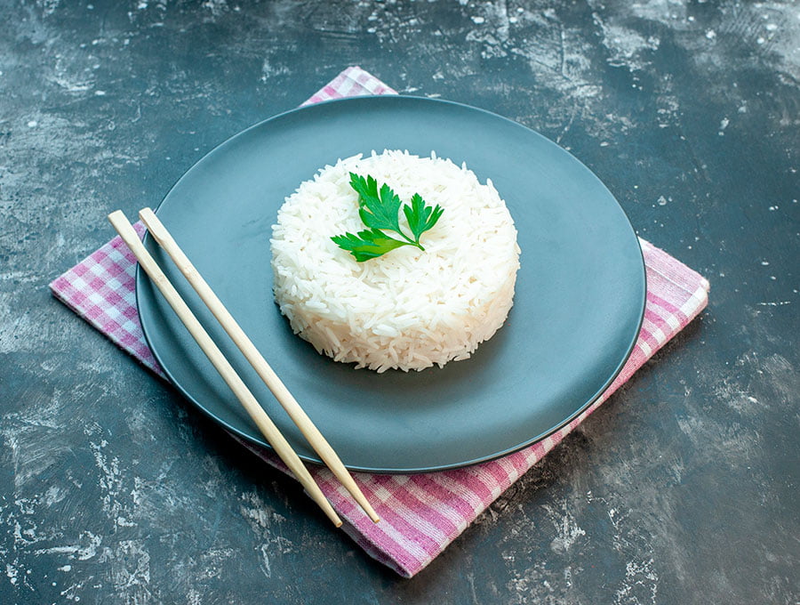 Un plato de arroz blanco con palillos para comer.