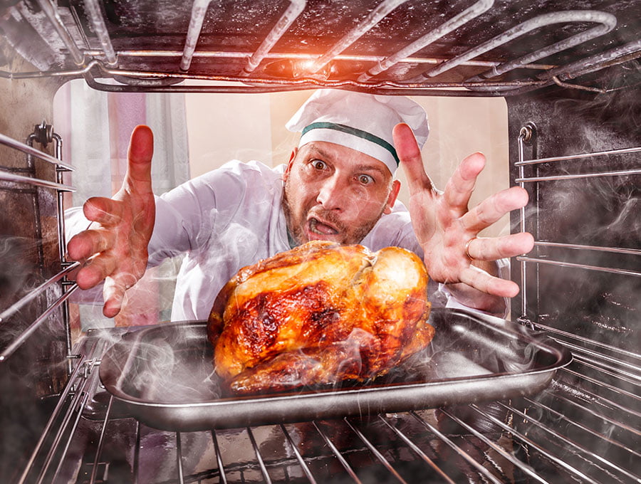 Hombre sorprendido al ver el buen aspecto que tiene el pollo asado que está cocinando en el horno.