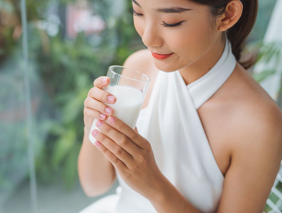 Esta mujer joven se está tomando un vaso de leche fría.