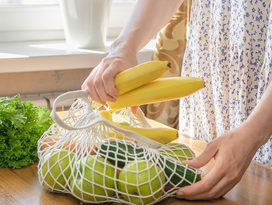 Esta mujer está cogiendo los plátanos de la bolsa de la compra para guardarlos.