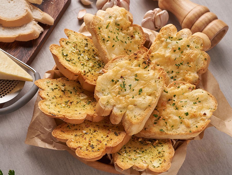 Plato con rebanadas de pan de ajo con queso fundido por encima.