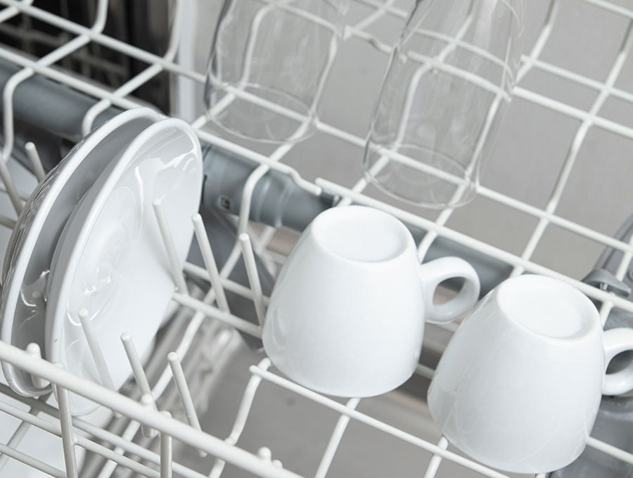 Las tazas limpias del café dentro del lavavajillas.