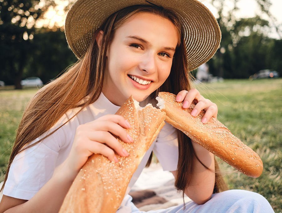 Mujer joven corta un trozo de pan caliente para comérselo.